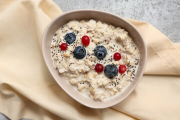 Bowl with tasty oatmeal, berries and chia seeds on grey grunge background