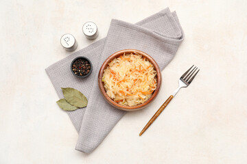 Bowl of tasty sauerkraut with bay leaves and peppercorns on napkin on white background. Top view