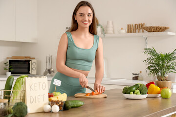 Sporty young woman cutting carrot in kitchen. Keto diet concept