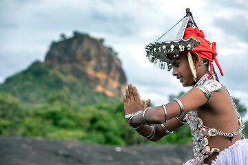 SIGIRIYA, SRI LANKA - JULY 16, 2024 : A Ves Dancer, also known as a Kandyan Dancer or Up Country Dancer performs at Sigiriya in Sri Lanka. In the background stands Sigiriya Rock.