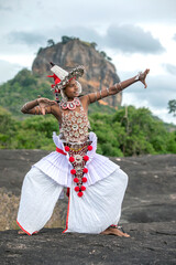 SIGIRIYA, SRI LANKA - JULY 16, 2024 : A Ves Dancer, also known as a Kandyan Dancer or Up Country Dancer performs at Sigiriya in Sri Lanka. In the background stands Sigiriya Rock.