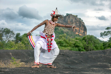 SIGIRIYA, SRI LANKA - JULY 16, 2024 : A Ves Dancer, also known as a Kandyan Dancer or Up Country Dancer performs at Sigiriya in Sri Lanka. In the background stands Sigiriya Rock.