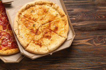 Cardboard boxes with delicious pizza on wooden background