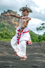 SIGIRIYA, SRI LANKA - JULY 16, 2024 : A Ves Dancer, also known as a Kandyan Dancer or Up Country Dancer performs at Sigiriya in Sri Lanka. In the background stands Sigiriya Rock.