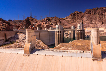 A large dam is seen in the distance with a blue sky in the background