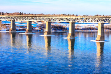 A bridge spans a river with a reflection of the bridge in the water