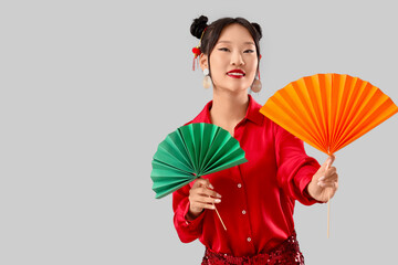 Obraz premium Beautiful Asian woman with paper fans on grey background