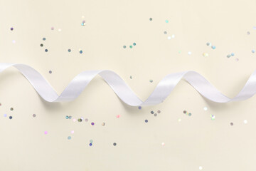 Silver glitters and white ribbon on light background