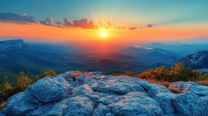 Fototapeta premium A stunning sunset over a mountainous landscape, showcasing vibrant colors and rocky foreground.