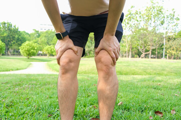 man with knee pain, he puts his hand on his knee, pain point from osteoarthritis and...