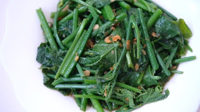 Table top view plate of  chayote leaves in Oyster sauce and garlic isolated on white background.