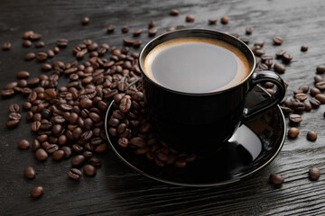 Cup of coffee on a saucer on a black background for breakfast