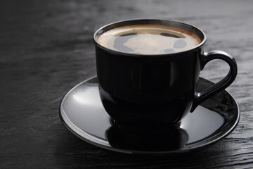 Cup of coffee on a saucer on a black background for breakfast