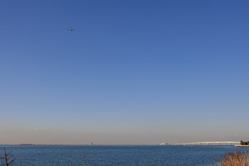 快晴の青空の中、飛行機が羽田空港に向かって飛行して行く