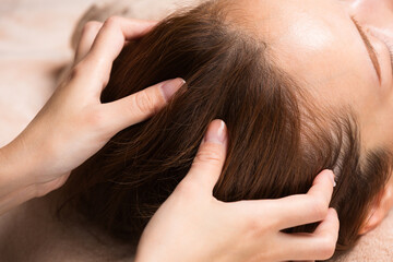 Fototapeta premium 若いアジア人女性はヘッドマッサージを受けています。