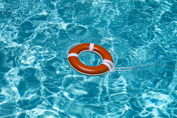 Safety equipment. Life buoy or rescue buoy floating on water. Ring for rescue. Help in water concept. Lifebelt on pool. Orange ring floating in pool water. Life buoy for protect and safety.