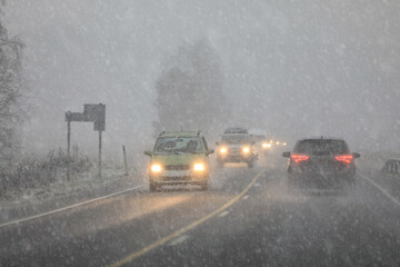 Driving in highway traffic with winter sleet and snow creating low visibility conditions, facing...