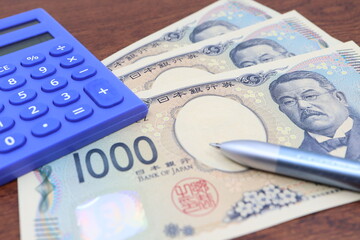 数枚の日本の千円札と電卓