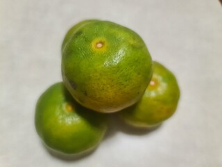 four tangerine, orange fruit with green, on a white wooden background texture, pyramid of fruit
