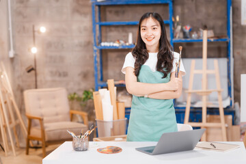 A cute Asian woman, a creative painter, works in her art studio.focuses on her painting,expressing her emotions and ideas through vibrant colors,creating beautiful artwork in a peaceful environment