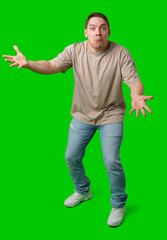 Young man in casual clothing stands with open arms against a vibrant green background