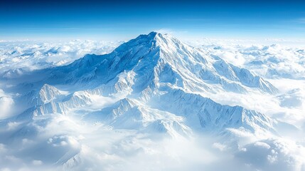 Obraz premium Majestic snow-capped mountain peak rising above a sea of clouds, viewed from an aerial perspective.