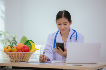 A female nutritionist holds a stethoscope to examine her health. She smiles and promotes healthy...