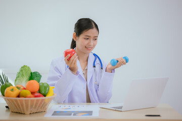 A female nutritionist holds a stethoscope to examine her health. She smiles and promotes healthy...