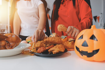 friendship, holiday and people concept - group of happy smiling friends in halloween costumes of vampire, devil, witch and cheetah at home party