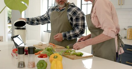 Couple preparing vegetables in kitchen, composting scraps, enjoying cooking together