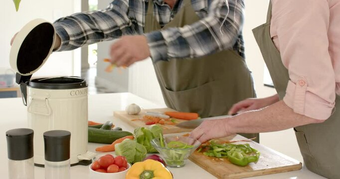 Preparing fresh vegetables, mature couple composting kitchen scraps at home