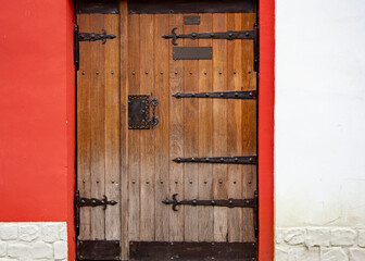 Close up of old wooden doors with heavy metal hinges in stone building