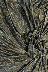 texture. A close-up abstract image featuring a textured, draped fabric-like surface with an earthy bronze and dark green patina finish. 