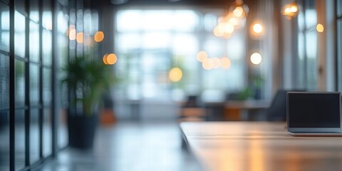 Abstract Blurred Office Workspace with Modern Decor and Natural Light Highlighting a Laptop on a Wooden Table in a Contemporary Setting
