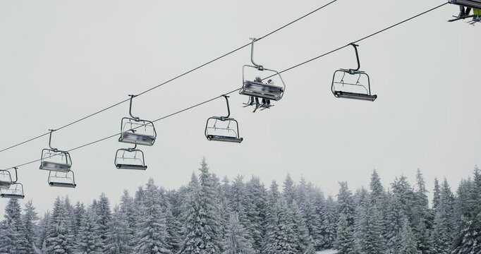Scenic winter landscape with chairlift above snow-covered forest during snowfall in Kopaonik, capturing serene mountain beauty and outdoor adventure on a calm, snowy day