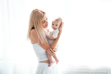 mom and baby hug and kiss, a young mother gently hugs a newborn baby girl holding her in her arms, maternal love and care, a young family, mother and daughter, a place for text