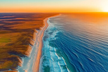 Naklejka premium A breathtaking aerial view of the sun setting over Sylt's coastline, creating an enchanting atmosphere with warm hues across land and sea, focusing on the stunning natural landscape.