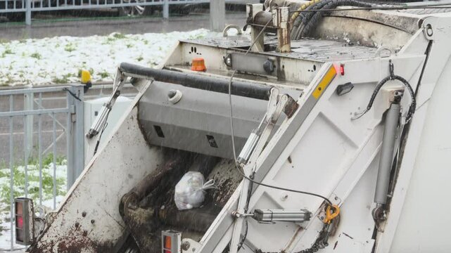 Rear loading waste collection garbage truck with bin tipper. Bin tipper mechanically lifts and inverts garbage bins in winter.