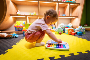 Kid enjoying musical playtime with a toy keyboard in a playful learning space