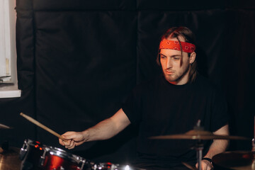 Professional drummer playing his drum kit during a live performance under dramatic lighting, creating a vibrant and energetic atmosphere