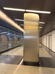 Fototapeta premium A large silver pillar stands in a long, empty hallway