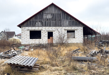 A dilapidated old house with a red roof and white walls
