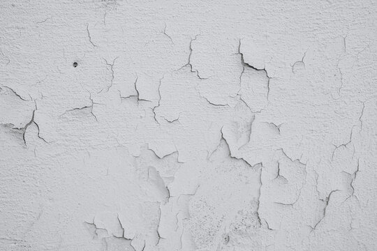 Cracked white wall texture revealing layers of deterioration in an indoor setting