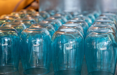 A row of blue plastic cups are lined up on a counter. The cups are all the same size and shape, and they are all clear. Concept of uniformity and order