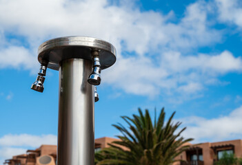 A tall metal pole with three sprayers on top. The sprayers are on the top of the pole, and they are...
