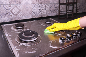 Woman cleaning gas stove with sponge and detergent. Cleaning kitchen. Housework and cleaning...