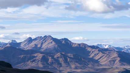 Fototapeta premium Majestic mountain range landscape showcasing a dramatic view of rugged peaks under a partly cloudy sky.