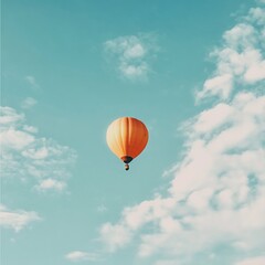 Fototapeta premium A bright orange hot air balloon glides gracefully through a clear blue sky, creating a stunning contrast. This image captures the essence of adventure and freedom.