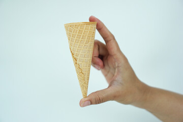 a woman's hand is measuring the length of an empty ice cream cone, isolated on white background