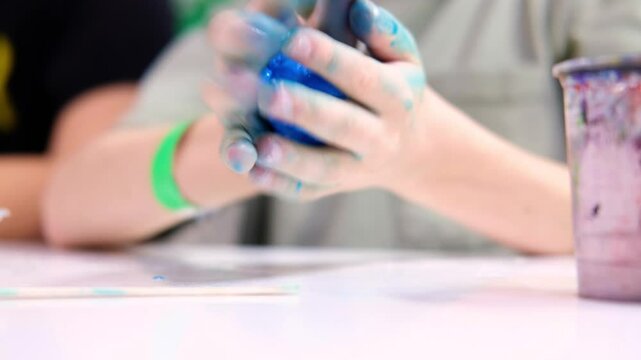 Boy making blue slime and kneading it in his hands, close-up